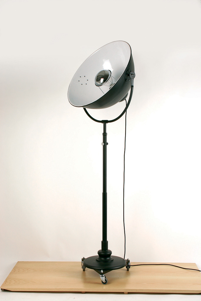 Floor lamp in black metal on wheels, like a projector. Contract&More. 