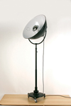 Floor lamp in black metal on wheels, like a projector. Contract&More. 